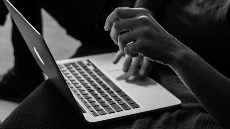 grayscale photo of person using MacBook